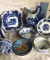 Assorted blue and white ceramic dishes including octagonal transferware plate, small floral dessert plate, scenic pitcher and various bowls