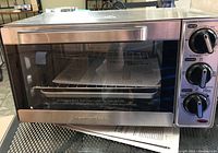 Front view of Hamilton Beach toaster oven with manual inside visible through glass door.