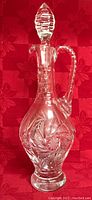 Photo of a pinwheel pattern crystal decanter with stopper, clear with intricate cut designs.