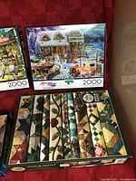 Photo of 3 puzzle boxes: Buffalo 2000-piece Winterland Fun, Buffalo 2000-piece Country Road, Cobble Hill 1000-piece quilt pattern puzzle.