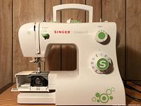 Front and side views of white Singer Esteem II 2273 sewing machine with green dials and decorative circle accents.