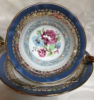 Top-down view of blue Staffordshire Versailles cup and saucer showing floral bouquet and gold filigree trim