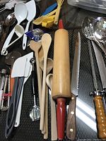 Various kitchen tools including wooden spoons, plastic spatulas, a rolling pin, and a serrated knife.