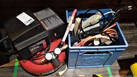 Porter Cable portable air compressor next to a blue box containing power bars and extension cables on the floor.