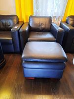 Leather armchair with faux leather ottoman in front, showing seating and armrests from a slight angle.