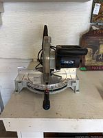 Full view of Delta ShopMaster chop saw with silver base and black handle, showing blade and angle adjustment.