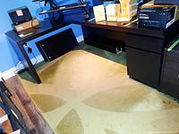 Full view of assembled L-shaped desk showing both sections against blue wall.