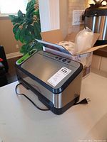 Angled side view of FoodSaver V4825 vacuum sealer with box of bag rolls behind
