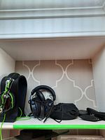Momentum headphones with lime green cord on Asona headset stand next to three sets of earbuds in cases and a black pouch.