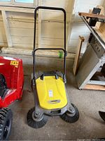 Full view of Karcher path sweeper showing yellow and gray body, black handle, and side brushes.