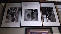 Set of three framed black and white nude photographic prints by Christian Coigny laid out on floor