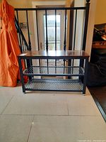 Front view of the shoe rack showing wooden top and two metal mesh shelves