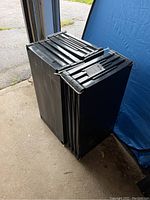 Three black plastic storage shelving units stacked and secured with zip ties, photographed from various angles showing frames and shelf surfaces.