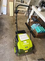 Front view of SunJoe scarifier and dethatcher showing overall unit and handle assembly.