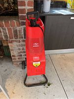 Front view of the red SunJoe CJ602E electric wood chipper with visible handle and intake chute, showing brand logo and 15A motor label.