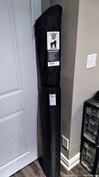 Rolled yoga mat in black carrying bag leaning against wall