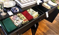 Drawer with cloth table napkins in solid green, red, and floral prints with mixed colors.
