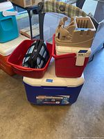 Stack of coolers and organizer including the red car organizer, blue and black Thermos insulated bag inside red small ice chest, and blue and white wheeled Coleman cooler at bottom