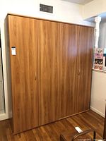 Front view of large wooden cabinet with closed bi-folding doors.