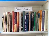 Shelf with varied preaching resource books, showing paperback and hardcover editions, with a hand-written 'Preaching Resources' sign above them.