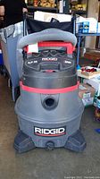 Front view of Ridgid wet/dry vacuum showing hose wrapped on top and brand name on body.