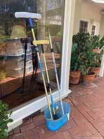 Full view of three extension poles standing upright in a blue bucket, one with a mop head attached, and a squeegee head visible
