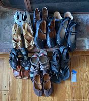 Top-down view of multiple pairs of women's shoes including sandals, flats, and heels in various colors and styles.