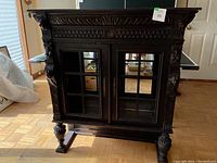 Front view showing carved oak cabinet with two glass panel doors