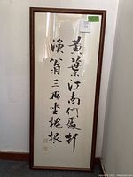 Full front view of framed Korean calligraphy panel leaning against wall showing signature and frame