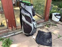 Side view of Callaway golf bag with multiple zippered pockets and green top, Mizuno shower cap placed beside it.