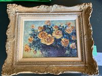 Frontal view of floral oil painting in ornate gold frame