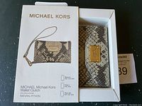 Michael Kors wallet clutch in natural python pattern in original box with signage showing compatibility for smaller iPhones.