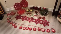Overview of all Christmas decor items spread on the floor including banners, wreath candle holders, various red felt snowflakes, and figurines.