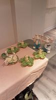 Eight Easter ceramic pieces including pastel-colored bunny figurines posed on green leaf bases and green leaf-shaped dishes with detailed texture