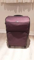 Front view of purple Samsonite suitcase showing main compartment and front zippered pocket.