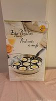 Front of box showing image of egg poacher pan with 6 eggs cooking inside.