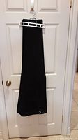 Black tuxedo pants hanging on a hanger, showing full length and adjustable waistband detail.