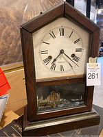 Front view of antique wooden gingerbread clock with dial and painted glass panel