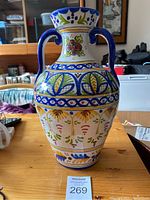 Front view of the ceramic vase showing the hand painted floral and geometric patterns and two handles.