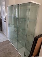 Front view showing three side-by-side clear glass display cabinets with white frames and tops.