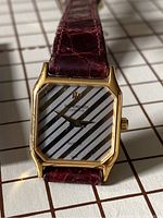 Rectangular gold-tone ladies Raymond Weil watch with striped dial and burgundy crocodile patterned leather strap.