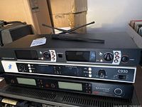 Three stacked professional audio rack units with wireless microphone antennas and various control interfaces.