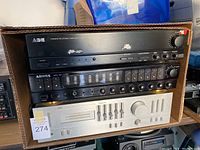 Photo showing the stacked stereo components including ADE amplifier on top, Arona equalizer in the middle, and JVC amplifier at the bottom inside a cardboard box.