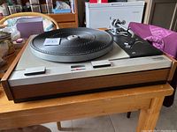 Side angle showing full turntable assembly and walnut plinth on wooden table