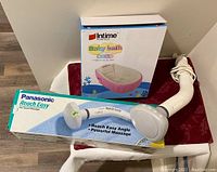 Massager in box next to boxed Intime inflatable baby bath, showing both items clearly for identification.