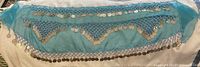 Full view of the blue Turkish hip scarf laid flat showing silver coin decoration and beadwork detail