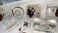 Full lot showing all nautical memorabilia on white fabric, including glass sail ship paperweight, acrylic lighthouse and ship decors, Join the Navy tile, sailor pin and pendant.