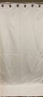 Full view of one white curtain panel with metal grommets at the top for hanging on a rod.