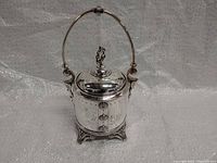 Front view of silver-plated jar with handle and lid, showing overall shape and shine.