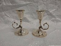 Pair of silver-plated candle stick holders shown side by side, front view to display shape and detailing.